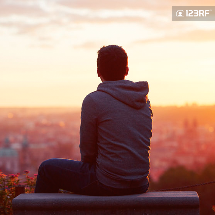 Stock Photo - Young man is looking at the sunrise.