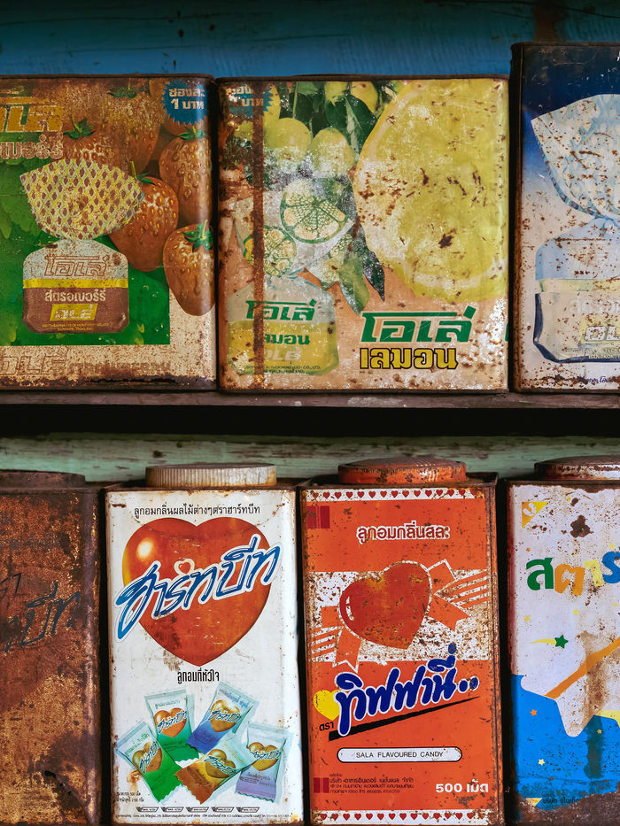 Shelf of weathered, colorful vintage tin cans and boxes with retro graphic labels