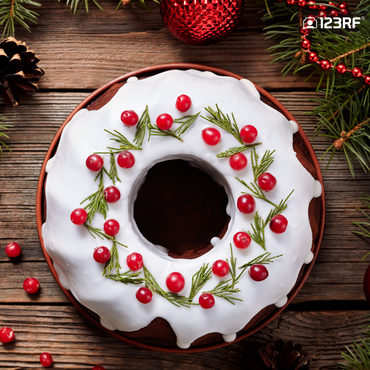 Stock Photo - Traditional homemade christmas cake holiday dessert with cranberry in new year tree decorations frame on vintage wooden table background. Rustic style. Top view