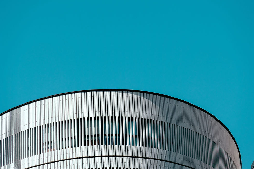 Curved white building facade with repeating vertical lines against a vivid teal sky