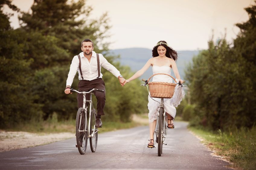 Stock Photo - Beautiful bride and groom riding on the bikes