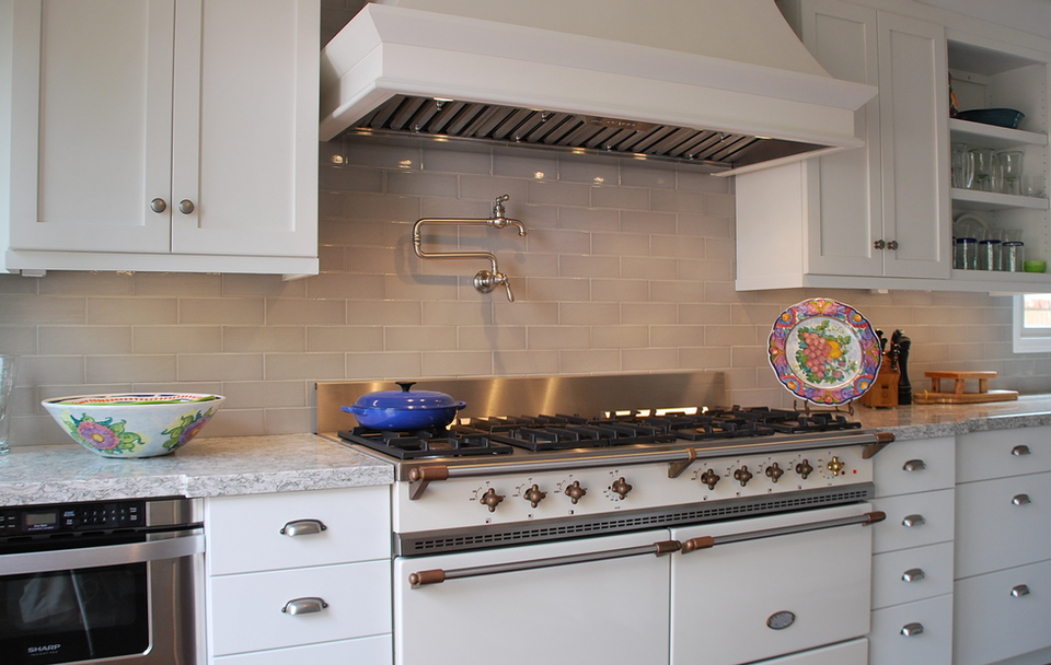 White kitchen with stove and cabinets, Legourmet Kitchen, granite countertops, and dishes.