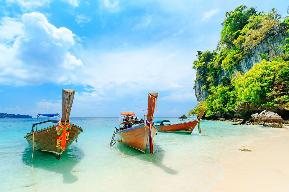 Three longtail boats on a white sand beach with turquoise water.