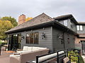 House exterior with dark gray siding, large windows, and outdoor patio