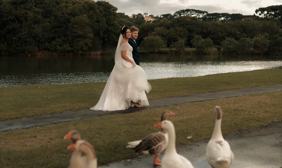 Newlyweds walking by a lake with geese in the foreground.