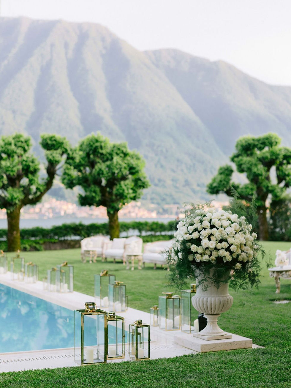 Outdoor wedding reception by a pool with mountain backdrop and decor.