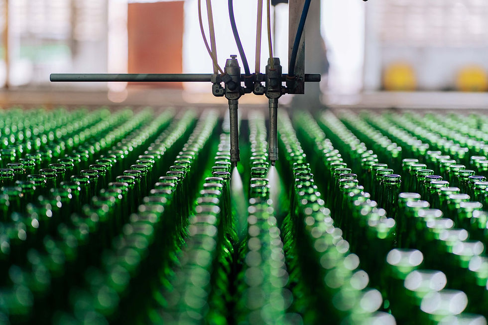 Automated nozzles spraying green glass bottles on a conveyor line.