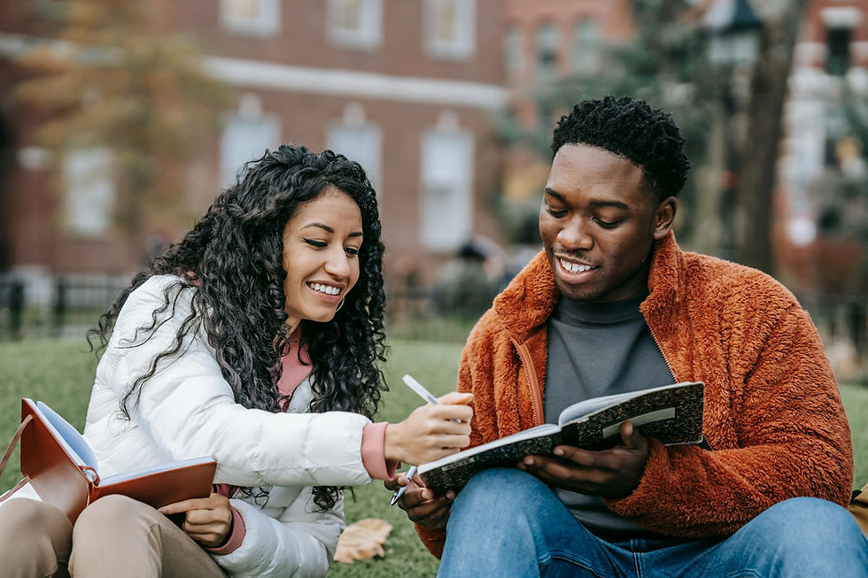 Two students reviewing notes together on campus, smiling and studying outdoors.