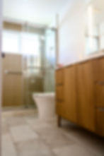 Modern bathroom with glass shower, wooden cabinet, and white toilet.