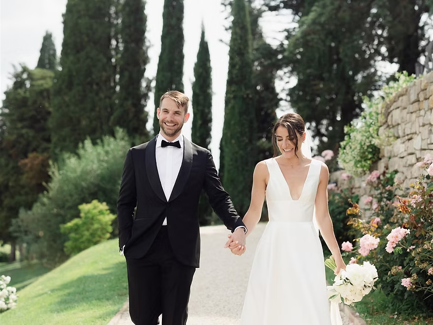 Smiling couple walking together, holding hands in a beautiful garden, wedding day bliss