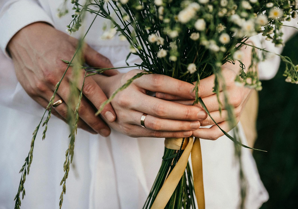 Couple holding wedding bouquet with rings on their fingers, celebrating love