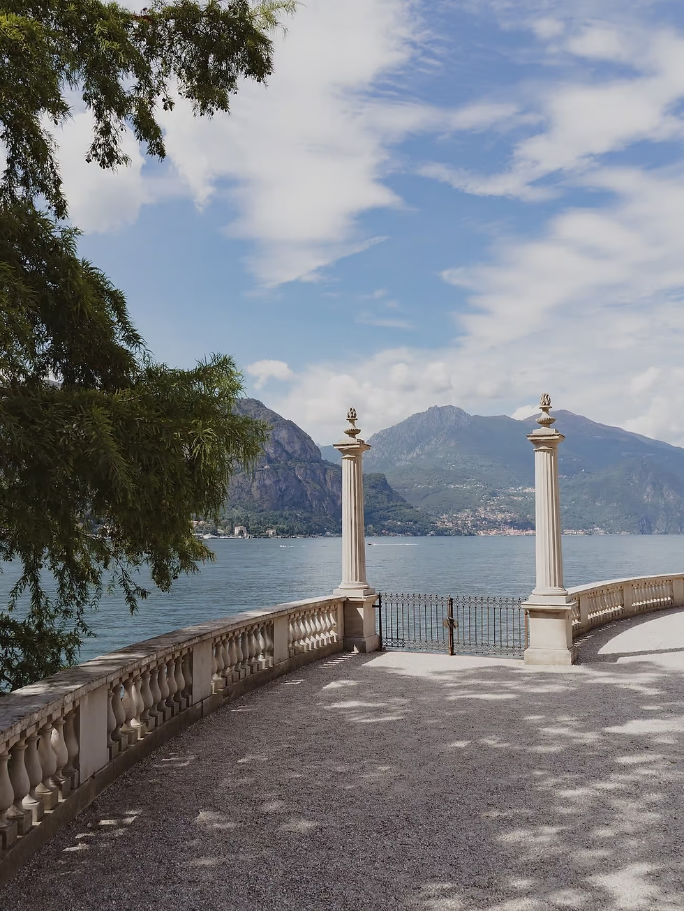 Vista mozzafiato sul lago con montagne, pilastri e balaustra in pietra.