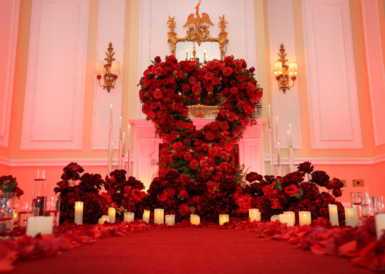 Red roses in heart shape, candles and romantic event setting.