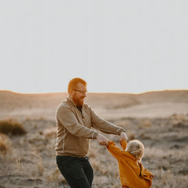Father twirling child at sunset