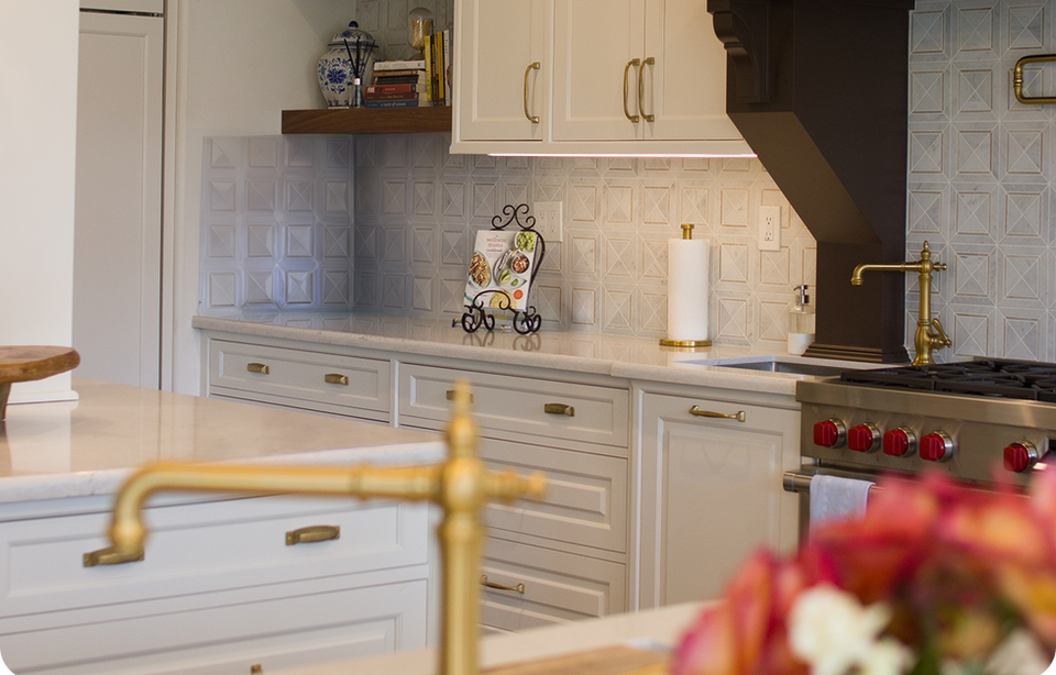 A clean, white kitchen with gold accents and a recipe book on display.