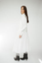 Woman modeling elegant white collared midi dress against a clean background.