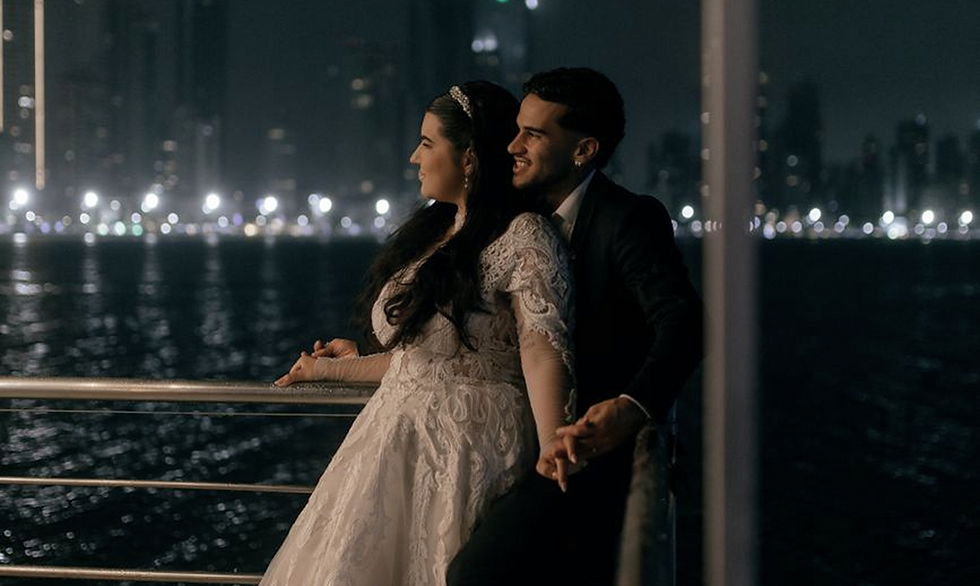 Newlyweds on a boat with the city skyline at night.