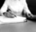 Person's hands writing on a document, calculator on desk.