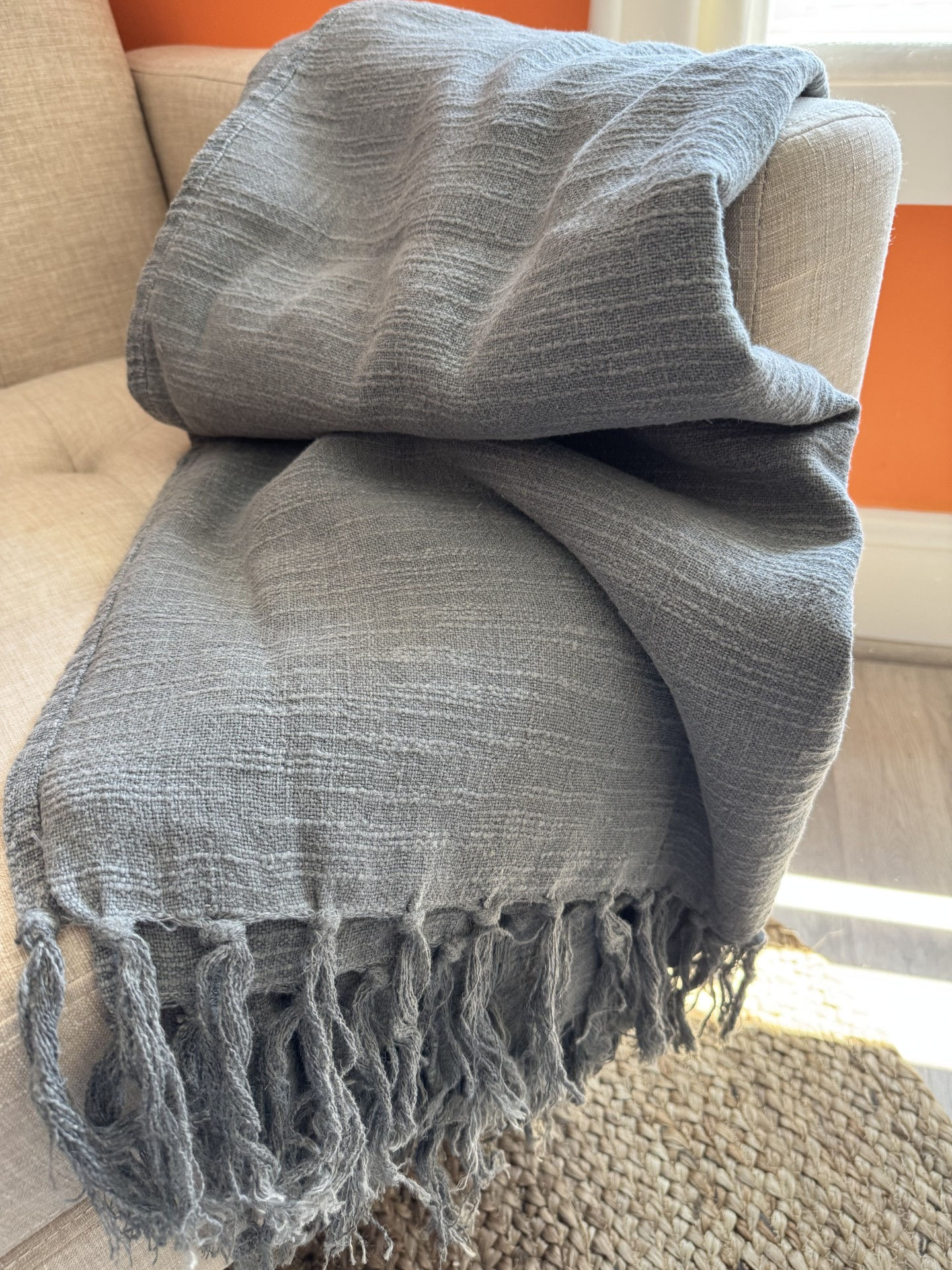 Grey linen throw draped over a neutral colored chair