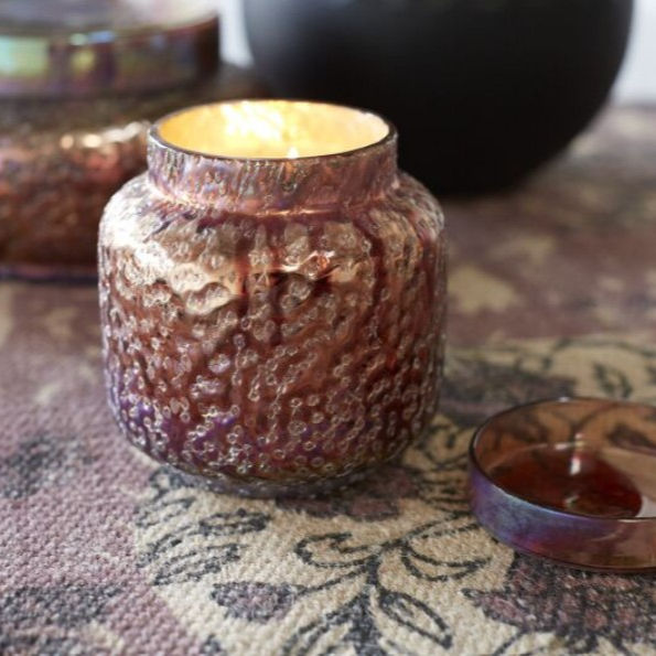 Textured glass candle jar with lid, shown lit.