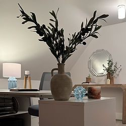 Decorative vase with greenery styled on console table beside mirror in warm neutral entryway