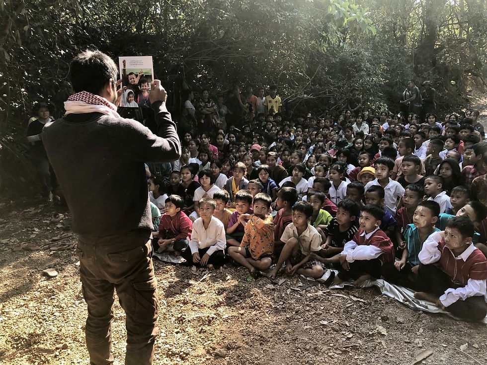 A Ranger displays an FBR publication to a group of displaced children.