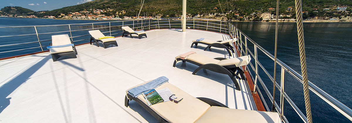 Sun deck loungers on Luna gulet under blue sky
