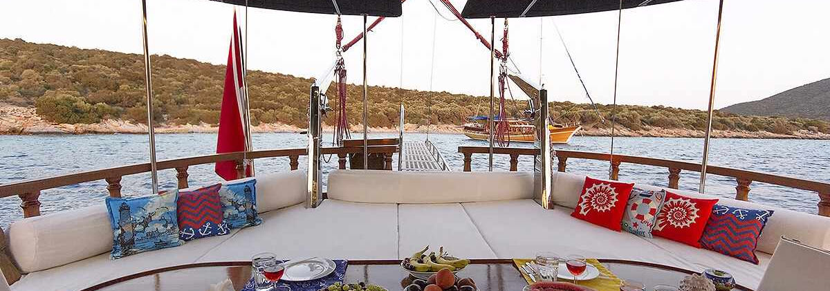 Cekin gulet aft deck dining table on teak deck under bimini shade