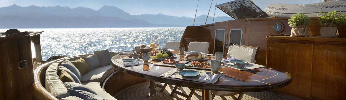 Virtuoso gulet aft deck dining table under shade on teak deck