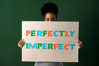 A woman holding a sign which says "Perfectly Imperfect"