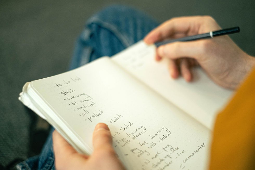 Over the shoulder view of a person writing a list in a notebook to represent mental load
