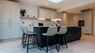 Modern shaker kitchen with a navy island, brass accents, and soft neutral cabinetry.