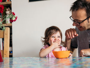 Dad and child exploring food together at a table