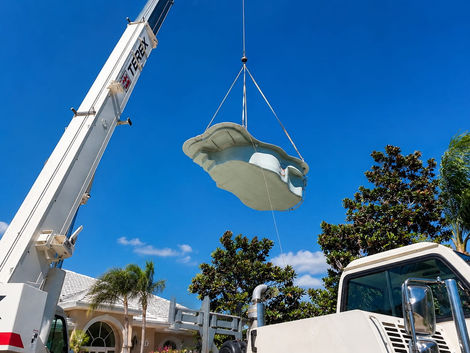 Large crane lifting a pre-formed swimming pool shell