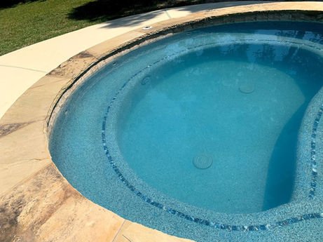 Round hot tub with blue water and stone coping