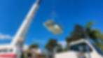 White crane lowering a pre-molded swimming pool shell.