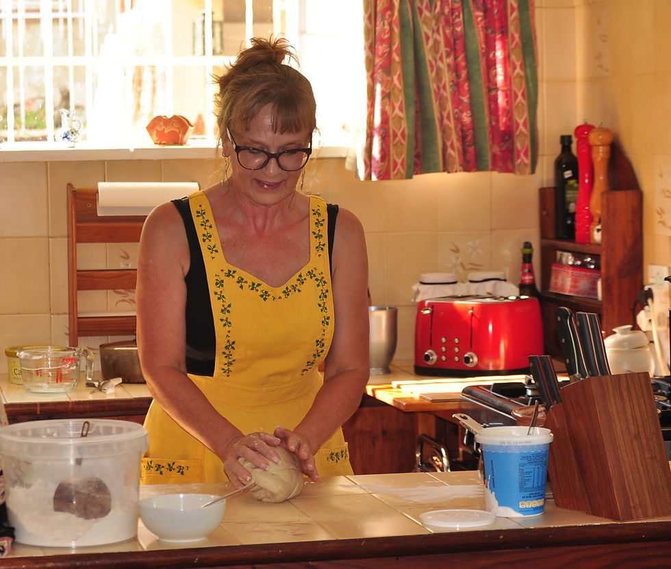 Image of a me kneading bread dough in the kitchen wearing my yellow embroidered apron.