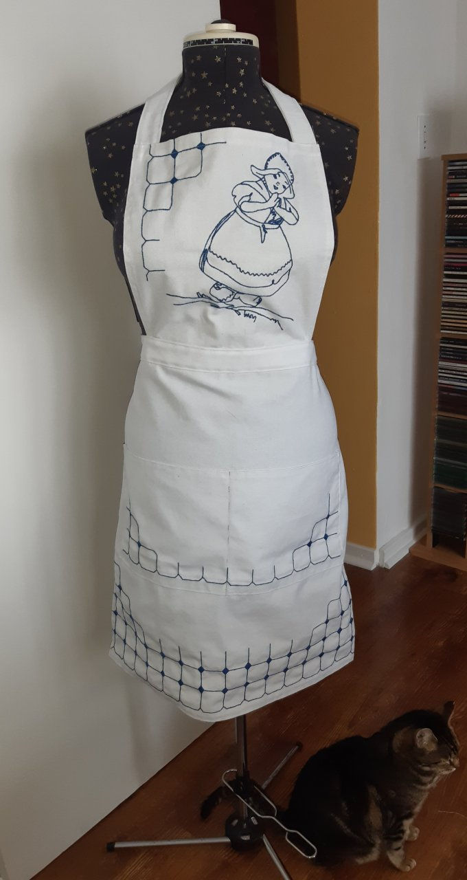 White apron with royal blue embroidery on the bib of a little Dutch girl, modelled on a dressmaker's doll