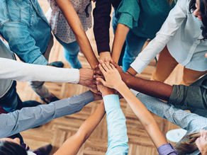 A diverse group of hands reaching inward to form a circle, symbolizing collaboration, inclusion, and support. Multiple hands of different skin tones join together at the center, representing the 'Dream Team' approach of teachers, parents, peers, and shadow teachers working together to support a student's success.