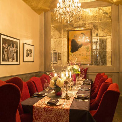 Elegant dining room set with red chairs, candles, artwork of the Private Dining Room of Crossroads Kitchen.