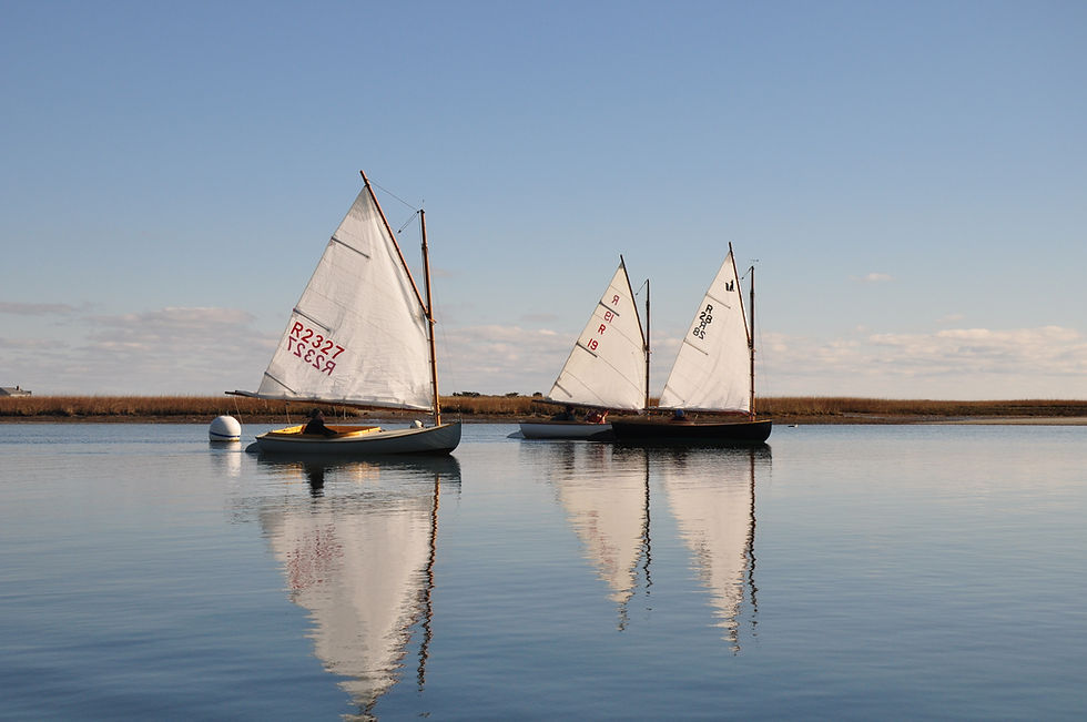 Small sailboats with white sails reflecting on calm water