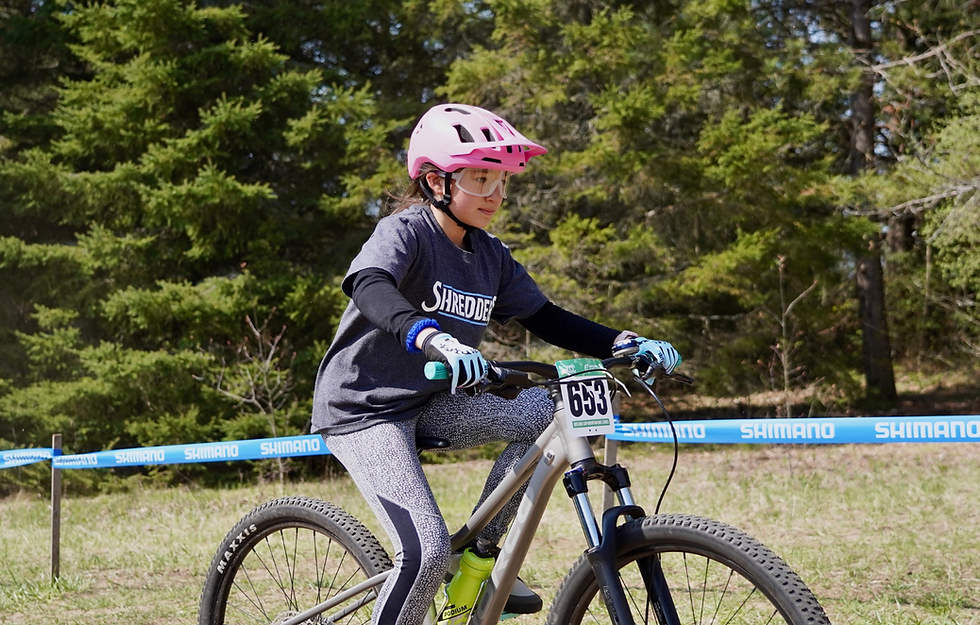 Girl in SHREDDERS shirt, pink helmet, riding mountain bike 653, Shimano.