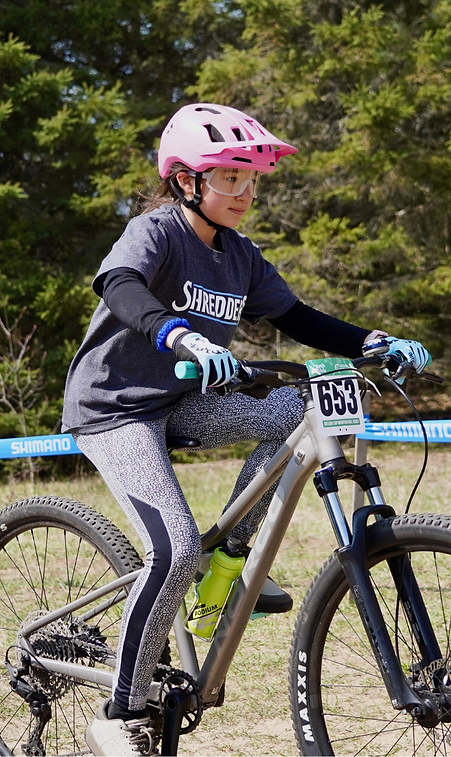 Young rider in pink helmet on mountain bike with number 653.