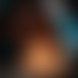 Fotograma de la película Niñas Escarlata. En un ambiente oscuro, una adolescente de piel morena y cabello rizado hasta los hombros está sentada frente a un pastel de cumpleaños blanco, mirando hacia abajo con expresión seria. Dos velas encendidas, con forma de los números «16», están clavadas en el pastel.