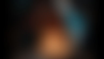 Fotograma de la película Niñas Escarlata. En un ambiente oscuro, una adolescente de piel morena y cabello rizado hasta los hombros está sentada frente a un pastel de cumpleaños blanco, mirando hacia abajo con expresión seria. Dos velas encendidas, con forma de los números «16», están clavadas en el pastel.