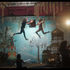 Dos personas bailan suspendidas en el aire en un escenario teatral, rodeadas de plantas, árboles y elementos decorativos, mientras otras personas observan y graban la escena.