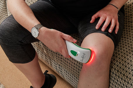 A Photizo Pain Relief red light therapy device being used on a knee