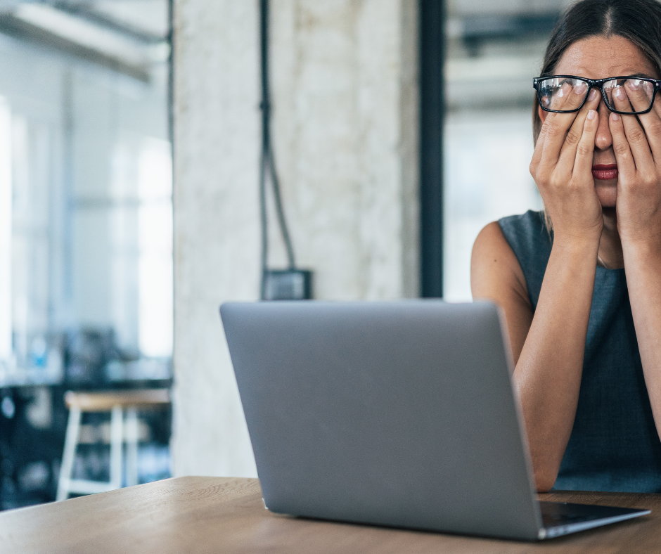 Lady covering eyes sat at laptop looking stressed