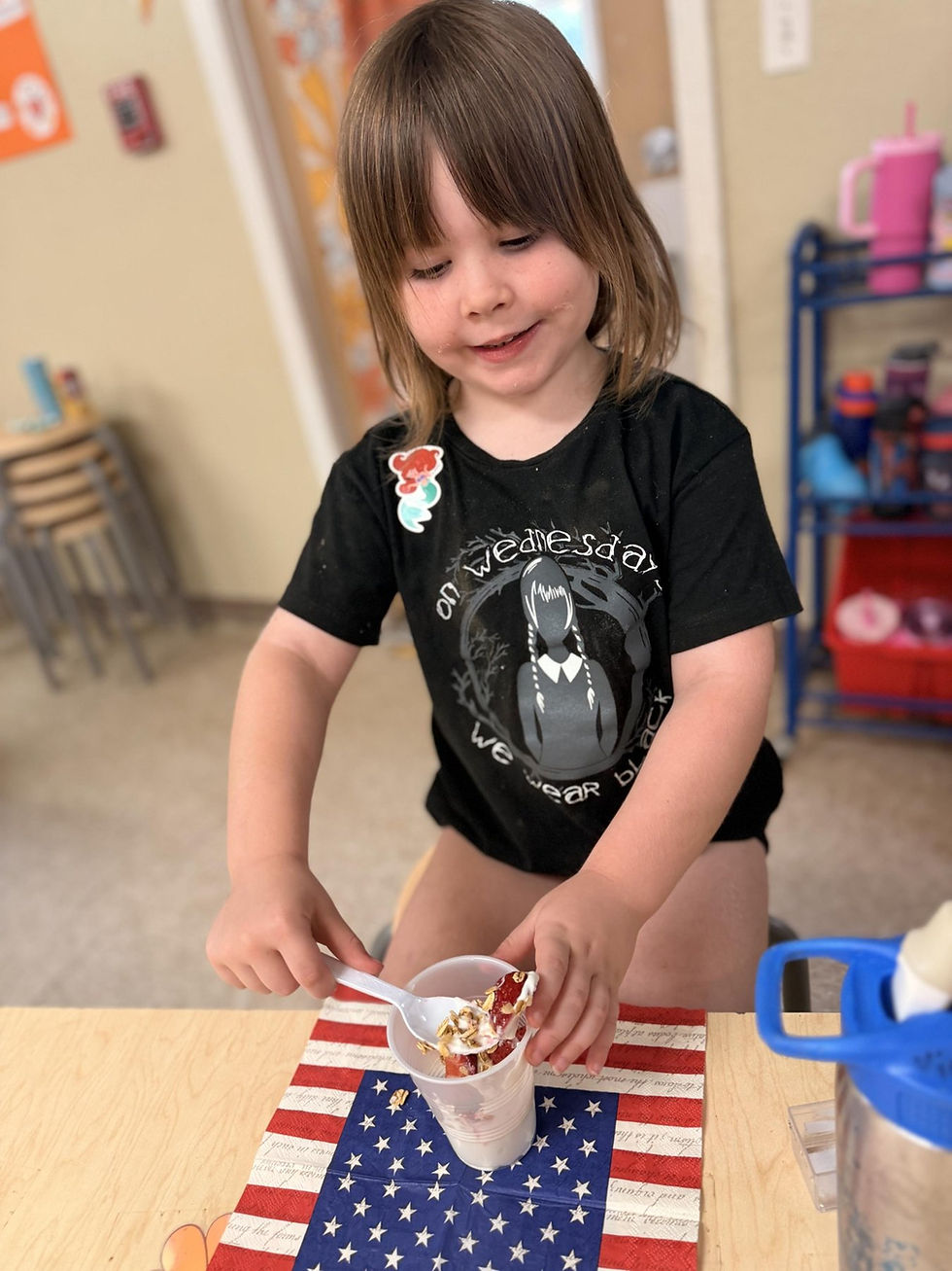 Preschooler spooning fruit and granola into a yogurt parfait during a K&A Nutrition visit