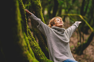 Overjoyed happy woman enjoying the green beautiful nature woods forest around her - concep